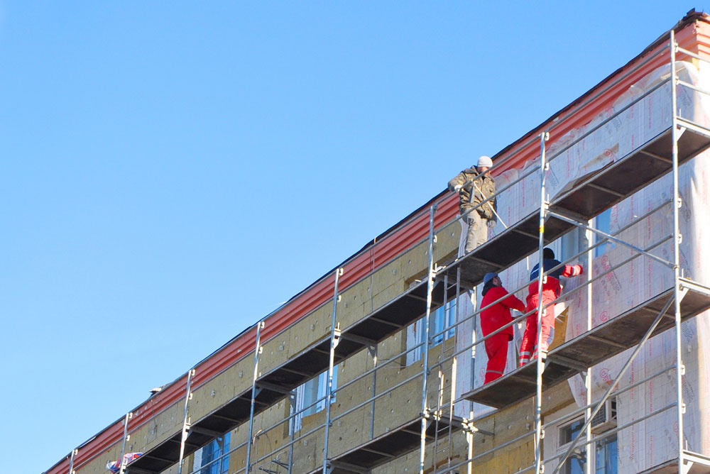Des ouvriers sur un échafaudage en train de rénover la façade d'un batiment